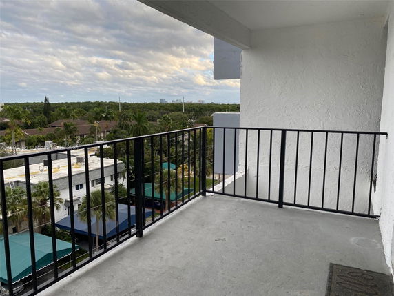 View of surrounding areas seen from a balcony, showing nearby buildings and greenery.