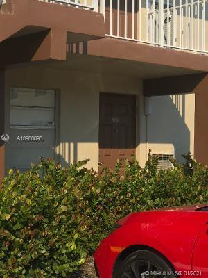Front view of a building entrance with a red car parked nearby.