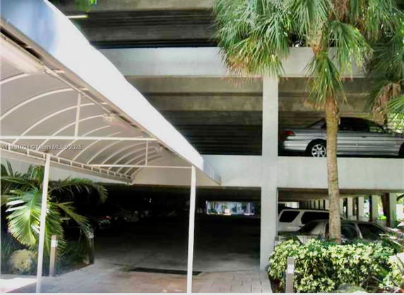 Covered parking area with multiple levels and parked cars.