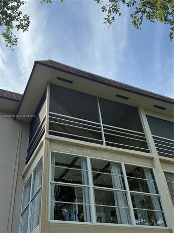 View of a house with large windows and a screened balcony.