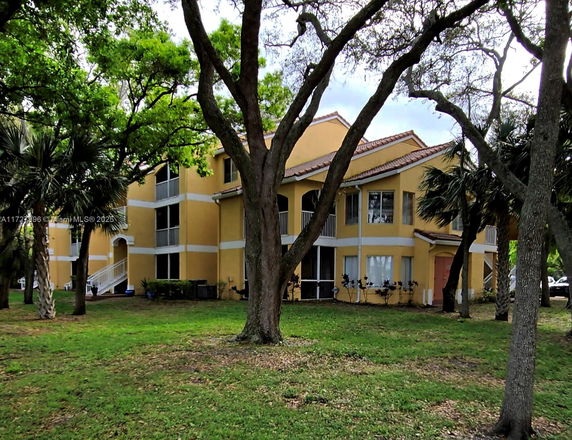 Front view of a two-story house with a yellow exterior and multiple balconies.