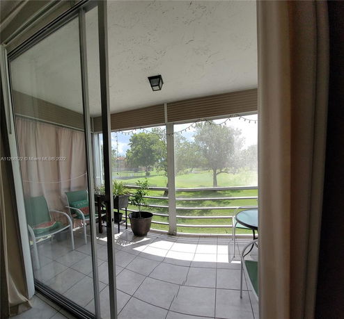 Covered outdoor patio with glass doors overlooking a grassy area.