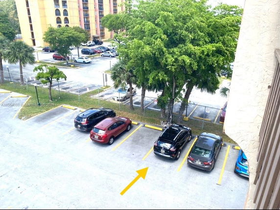 Outdoor parking lot with several parked cars and surrounding trees.