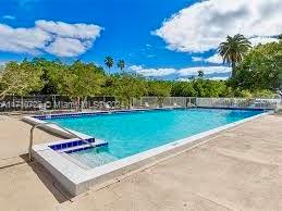 Outdoor swimming pool with surrounding trees and clear sky.