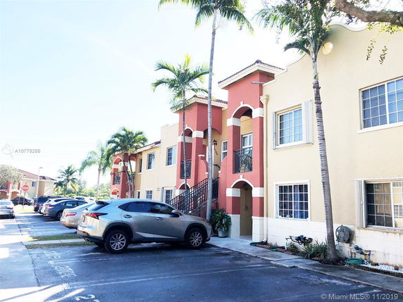 Front view of a two-story residential building with external stairs and parking area.