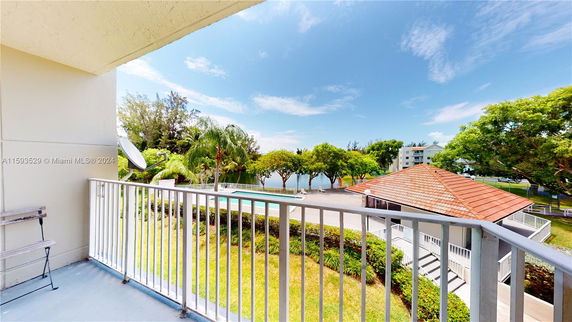 Balcony view overlooking a swimming pool and surrounding greenery.