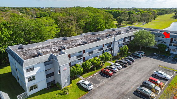 Aerial view of a multi-story building with a flat rooftop featuring air conditioning units.