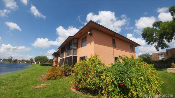 Side view of a two-story house near a lake with a garden.