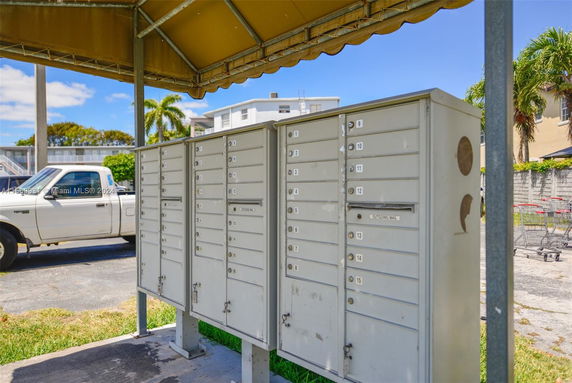 Outdoor mailboxes under a small shelter with a pickup truck in the background.