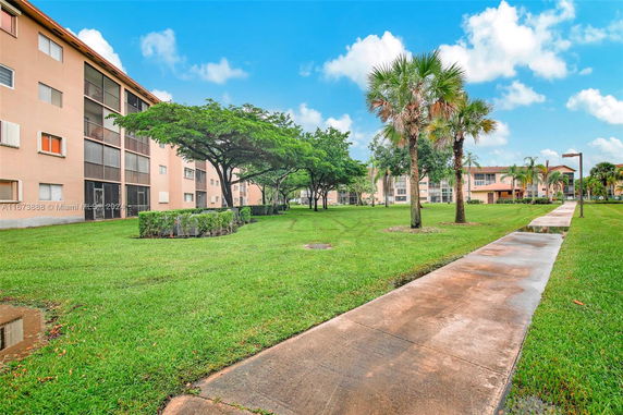 View of a walkway and grassy area surrounded by multi-story apartment buildings.