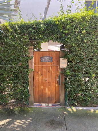 Front view of a wooden gate with greenery around.