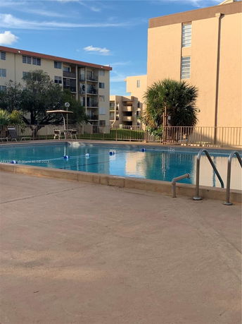 View of a swimming pool with apartment buildings in the background.
