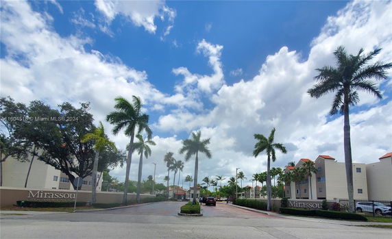 Front view of a multi-story condominium building with palm trees.