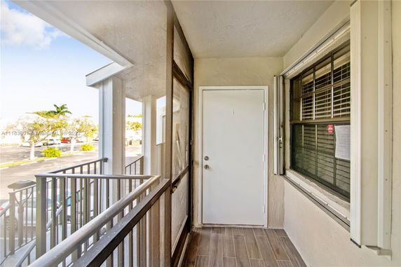 View from a balcony with a door and window, overlooking a parking area.