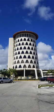 Front view of a circular, multi-story building with a unique pattern of arch-like windows.
