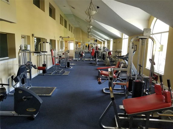 Indoor gym area with various exercise equipment and machines.