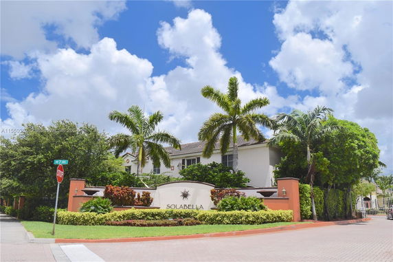 Front view of a residential building with palm trees and a sign reading 'Solabella'.