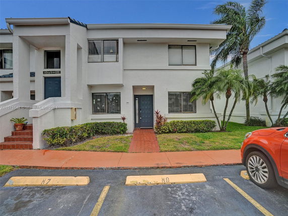 Front view of a two-story townhouse with a main entrance and surrounding plants.