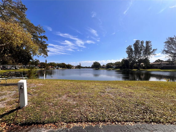 Scenic view of a lake with surrounding trees and houses visible on a clear day.