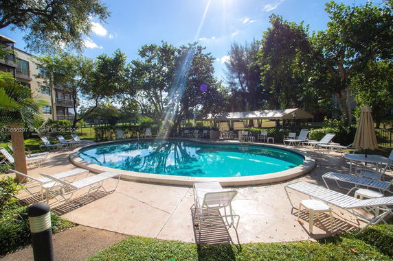 Outdoor swimming pool surrounded by lounge chairs and trees.