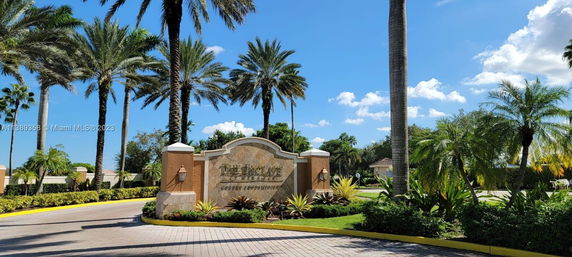 Entrance view of a luxury condominium with palm trees and a decorative sign.