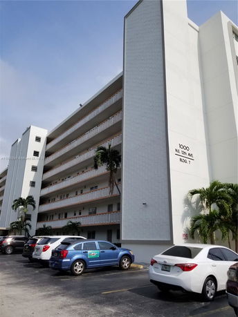 Front view of a multi-story residential building with balconies and parking area.