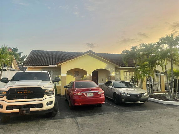 Front view of a house with a tile roof and parking area.