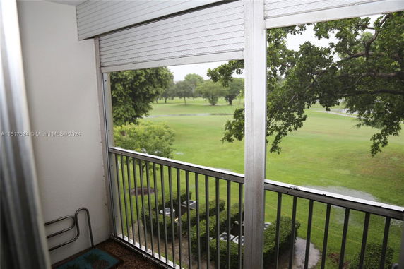View outside from a balcony with greenery and trees visible.