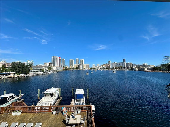 Panoramic view of a waterfront with city skyline and boats docked.