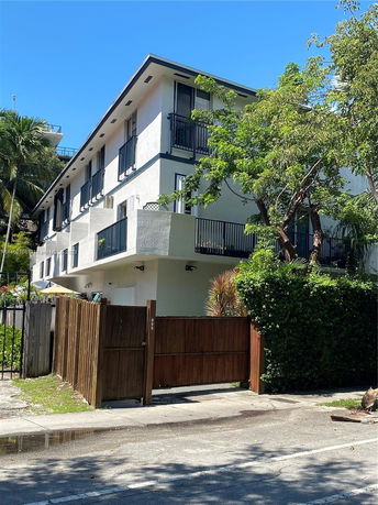 Front view of a two-story building with balconies and a wooden fence.