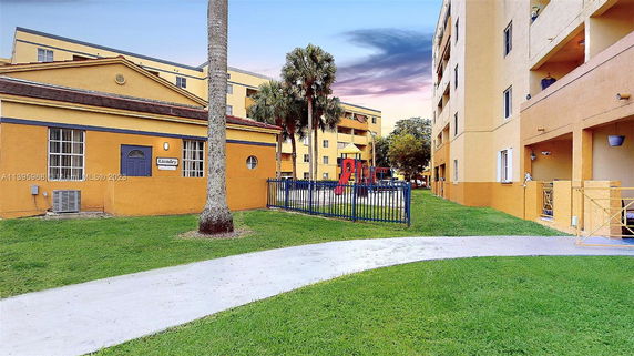 View of a laundry building and adjacent fenced playground with multi-story buildings nearby.