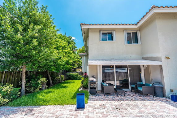Side view of a two-story house with a patio area and garden.
