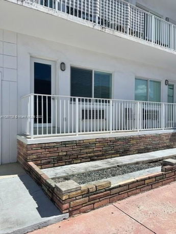Front view of a building with a white railing and stone platform.