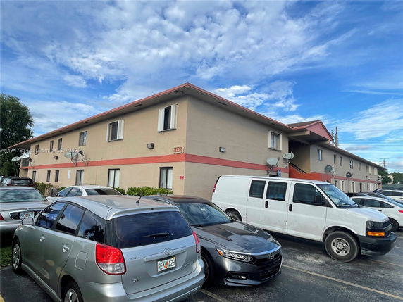 Front view of a two-story apartment building with surrounding parking area.
