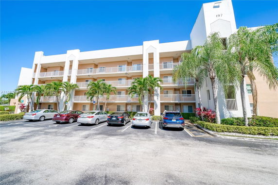 Front view of a four-story apartment building with parking in front.