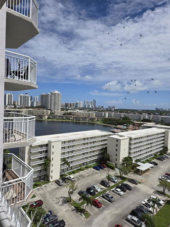 View of multiple mid-rise residential buildings with parking lots and a waterway in the background.