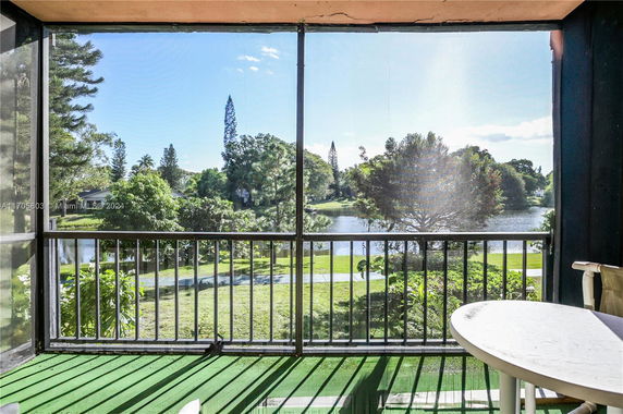 View from a balcony overlooking a lush landscape with a lake and trees.