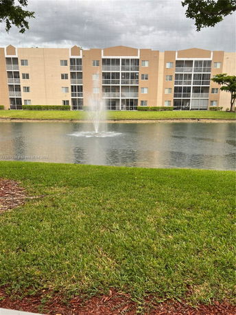 Rear view of a multi-story building overlooking a pond with a fountain.