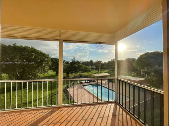 View of a swimming pool and grassy area from a balcony.