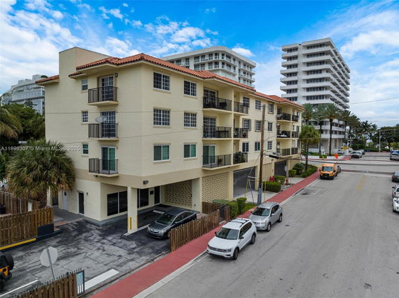 Front view of a multi-story residential building with balconies and parking area.