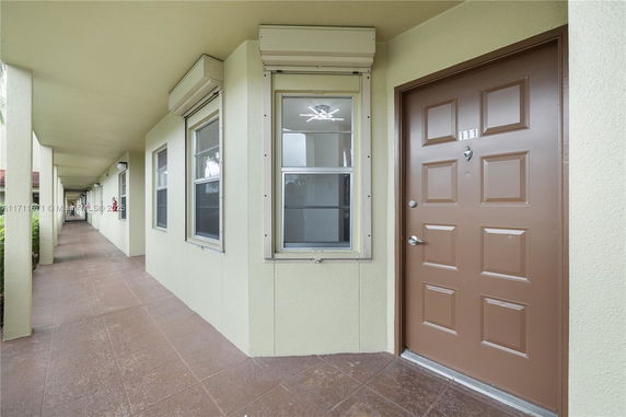 View of an apartment corridor with door and windows.
