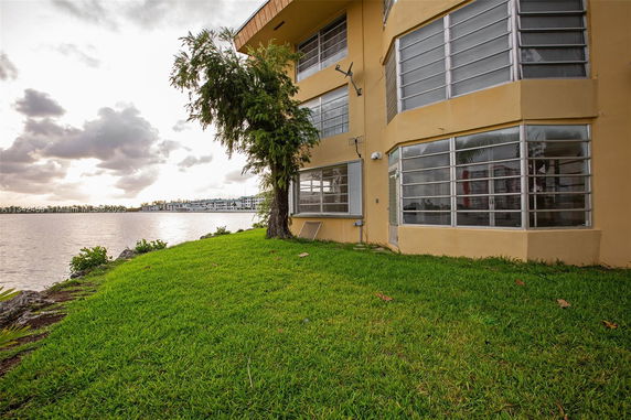 Side view of a multi-story building with large windows, located next to a body of water.