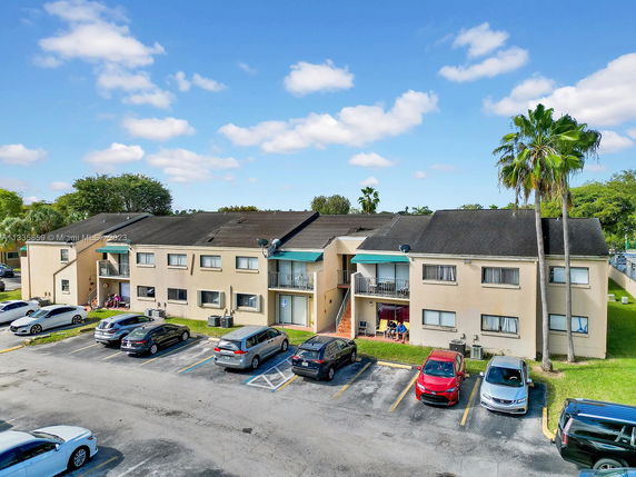 Front view of a two-story apartment building with parking spaces in front.