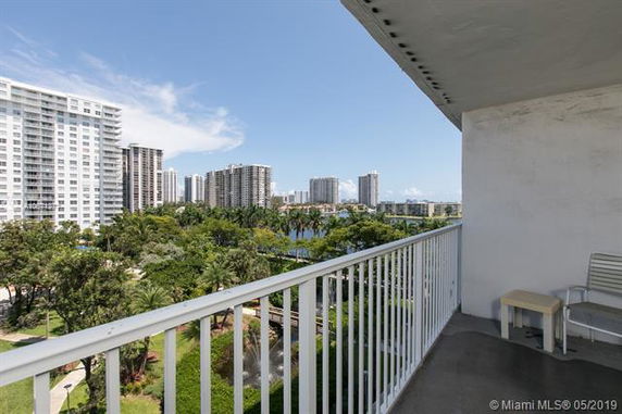 View from a balcony overlooking a park and high-rise buildings.