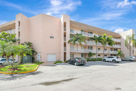 Front view of a multi-story residential building with balconies and parking area.