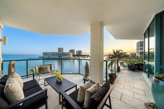 Balcony with a scenic view of waterfront buildings and sunset.