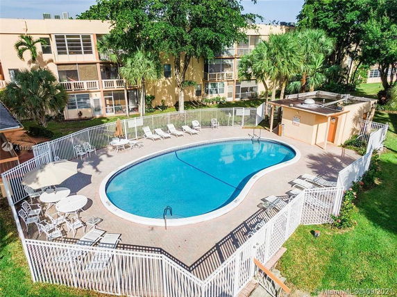 Outdoor swimming pool area with surrounding fence and lounge chairs.