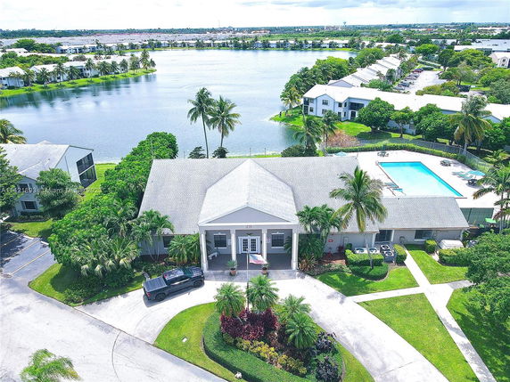 Aerial view of a large house with a lake and a community pool.