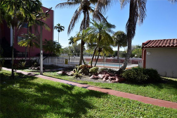 Outdoor view of a swimming pool area surrounded by palm trees and a walkway.