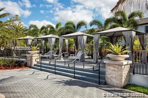 Outdoor area with seating and cabanas by a poolside.